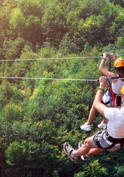 Zipline is an exciting adventure activity. Man and woman hanging on a rope-way. Tourists ride on the Zipline through the canyon of the Tara River Montenegro. Couple in helmets is riding on a cable car